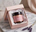 Pūraka Brightening Soothing Hand Cream in amber glass jar nestled in a pink gift box with white tissue paper, styled on marble with dried lavender