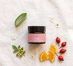 Pūraka Eye Cream flatlay with aloe vera, orange slices, rosehip and botanical flowers