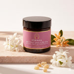 Pūraka Active Day Cream jar with jasmine and neroli flowers on blush stone surface