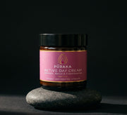 Pūraka Active Day Cream in amber glass jar balanced on dark stone
