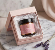 Pūraka Brightening Soothing Hand Cream in amber glass jar nestled in a pink gift box with white tissue paper, styled on marble with dried lavender