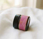 Pūraka Eye Cream in amber glass jar resting on soft white linen in natural window light
