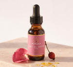 Pūraka Face Oil Serum Rose dropper bottle with rose petal and rosehip on blush stone