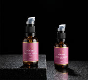Pūraka Face Serum Oil amber glass pump bottles on stepped black granite surface