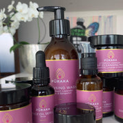 The full Pūraka natural skincare range displayed together — including Cleansing Wash, Face Oil Serum, Hydrating Face Scrub, Hydrating Super Serum, Eye Cream, and Activated Charcoal Deep Cleansing Mask in amber glass packaging